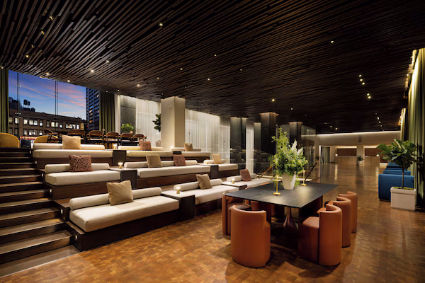 A modern lounge area with tiered seating, a central table, and a staircase leading to upper levels.