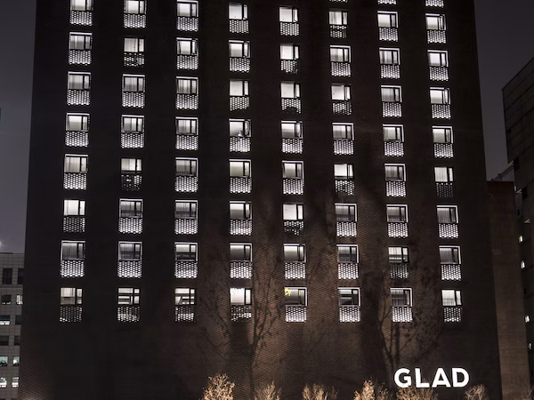 A high-rise building with multiple windows, a visible entrance, and the word "GLAD" on the facade.