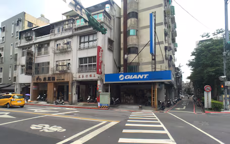 A street view with a crosswalk, a yellow taxi, and a building with a 'GIANT' sign.