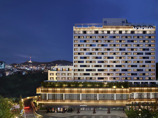 A high-rise hotel with multiple floors, a prominent "MONDRIAN" sign, and a well-lit entrance area.