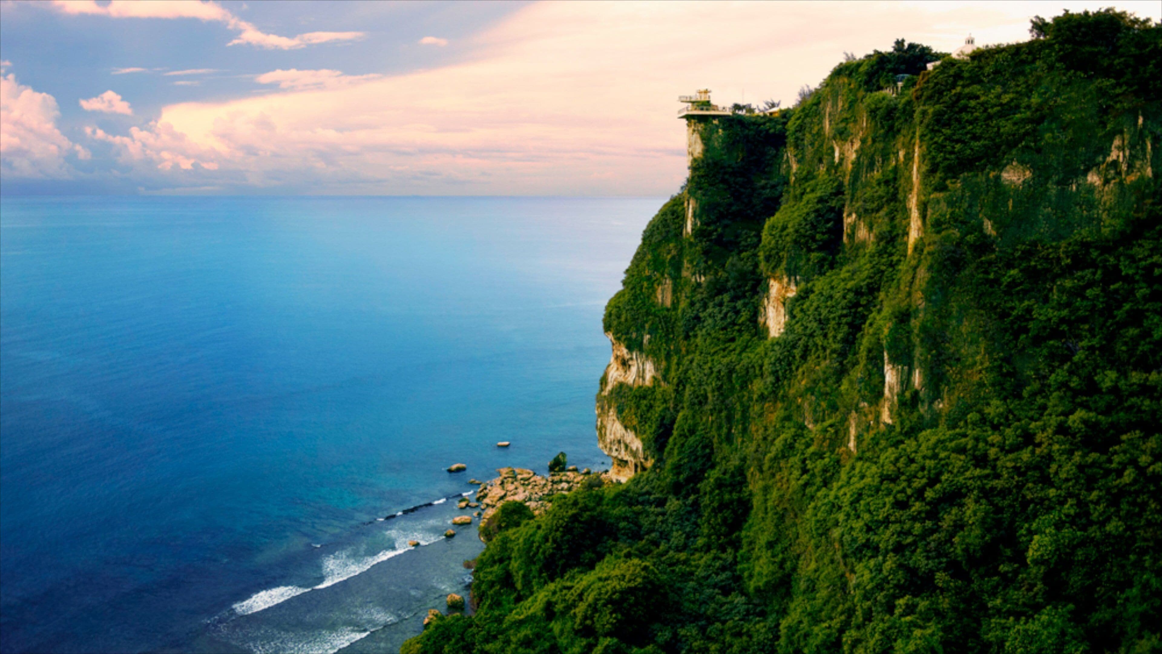 A coastal cliff with a lighthouse on top, overlooking the ocean.